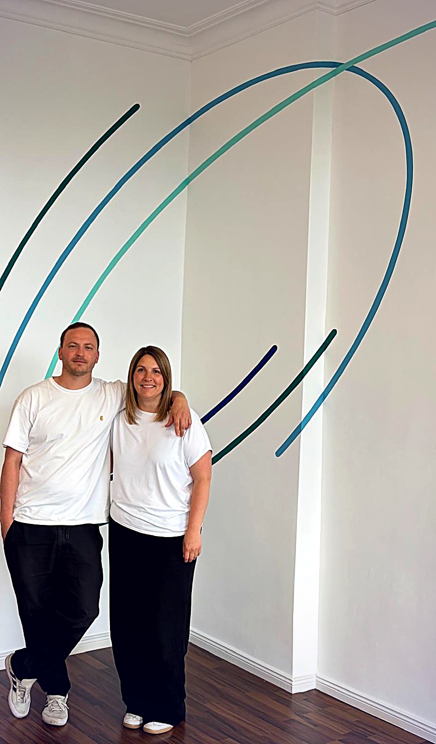 Philip Wallisfurth und Sylvana Engel von WE/C vor einer Wandarbeit in Blau- und Grüntönen